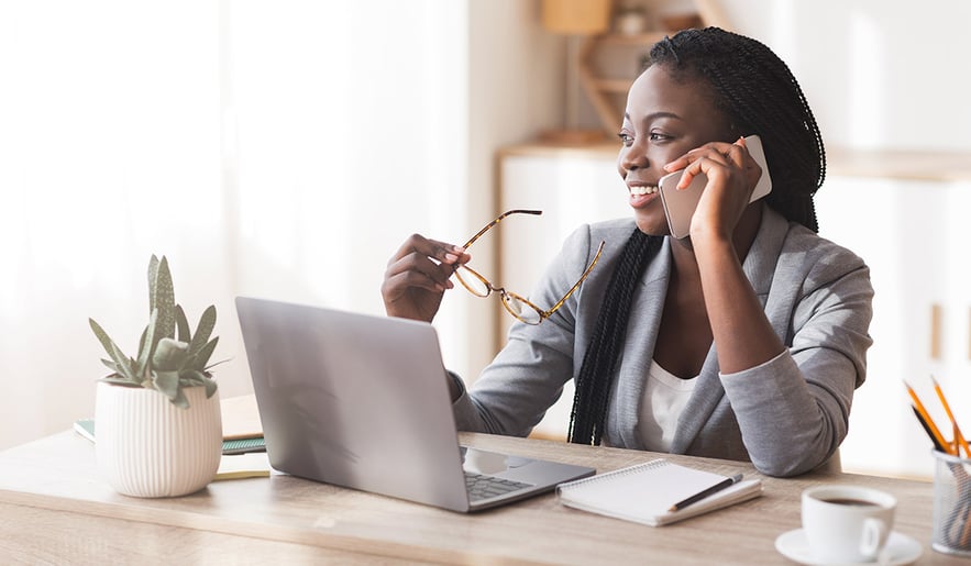 woman-chatting-on-her-phone-sitting-at-a-desk