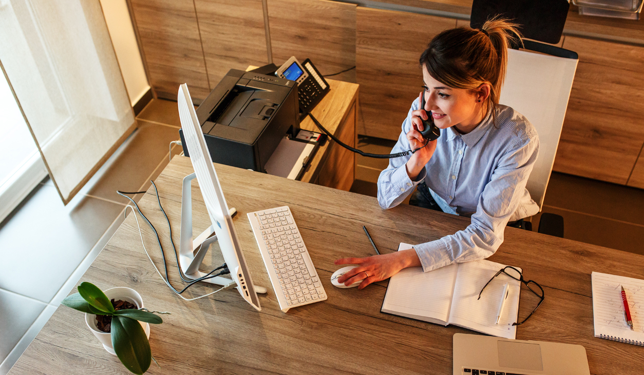 Woman using phone in office with desktop