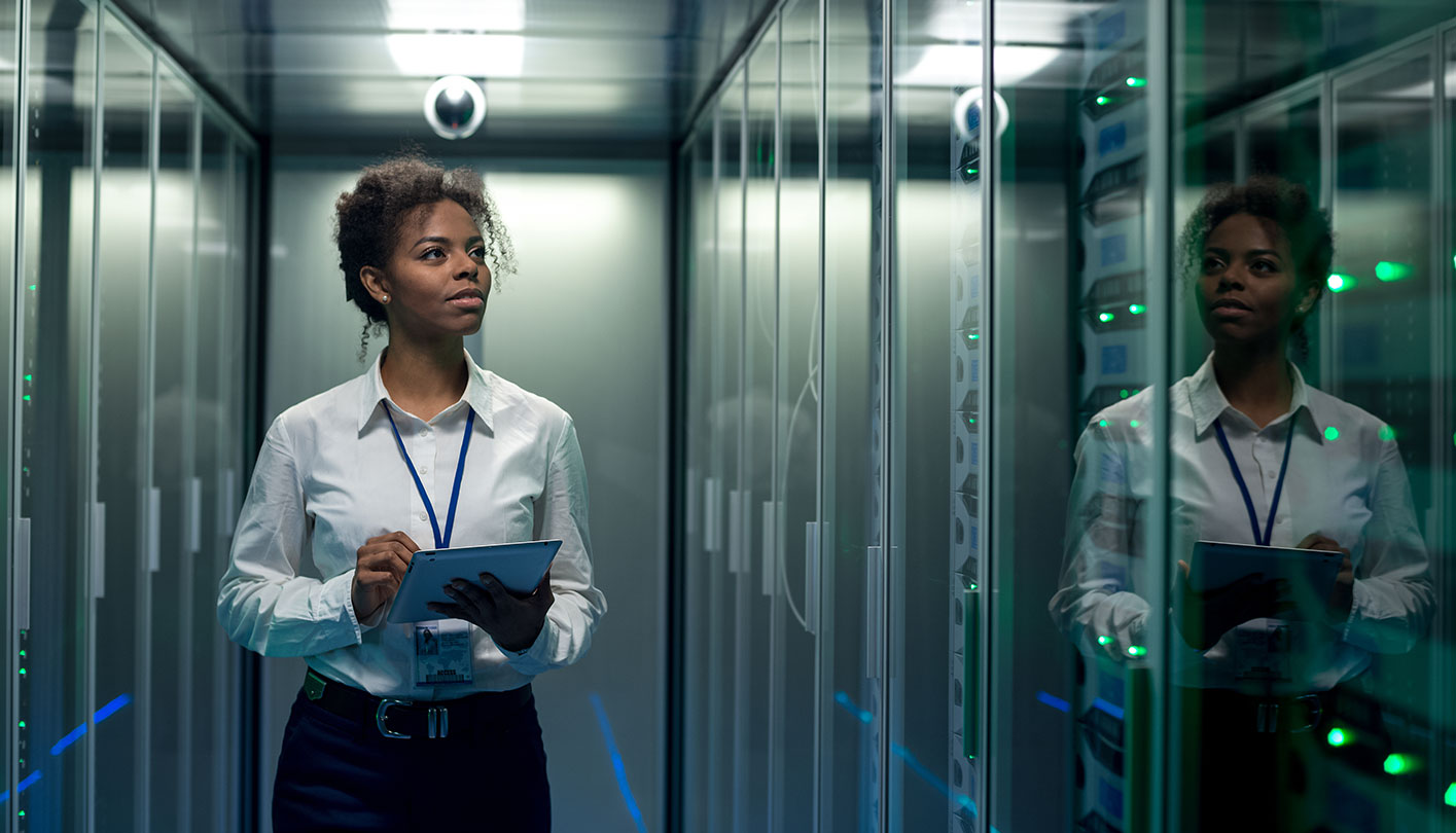 woman with notepad monitoring server racks